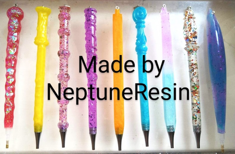 May include: A collection of ten colorful resin pens with glitter and various designs. The pens are made by NeptuneResin.
