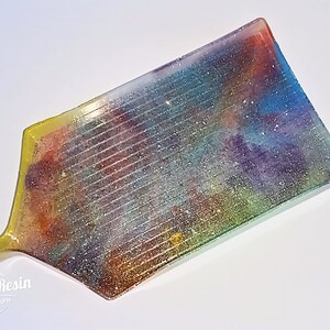 May include: A rectangular tray with a colorful, glittery resin design. The tray has a yellow border and a slightly curved edge.
