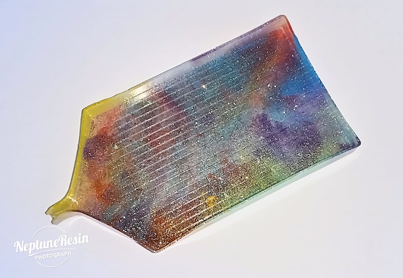 May include: A rectangular tray with a colorful, glittery resin design. The tray has a yellow border and a slightly curved edge.