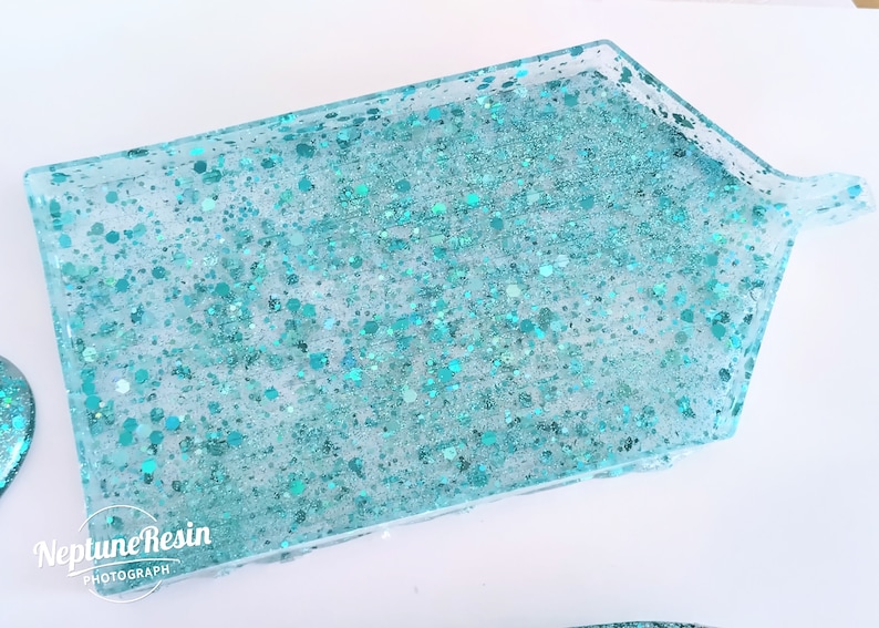 May include: A turquoise resin tray with a handle. The tray is filled with turquoise glitter.