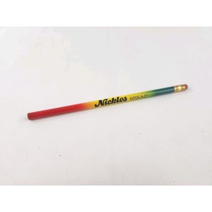May include: A pencil with a gradient color scheme, transitioning from red to yellow to green. The pencil has the text "Nickles BREAD" printed in black. The eraser is pink.