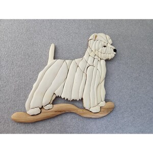 May include: A cream-colored, wooden dog sculpture, possibly a West Highland White Terrier, is depicted standing on a curved wooden base. The dog is constructed from numerous small, rectangular pieces, with a black nose and eyes. The background is a solid gray.