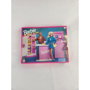 May include: A vintage Barbie "So Much To Do!" Bank playset box. The box features a pink and blue design with Barbie figures at a bank counter and ATM. The Barbie logo is prominently displayed.