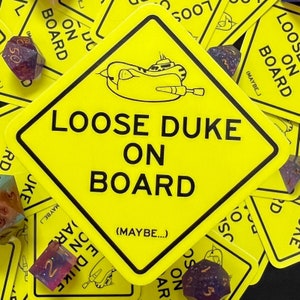 May include: Yellow warning sign with black text that reads "Loose Duke On Board (Maybe...)". The sign is shaped like a diamond and has a cartoon submarine on it.