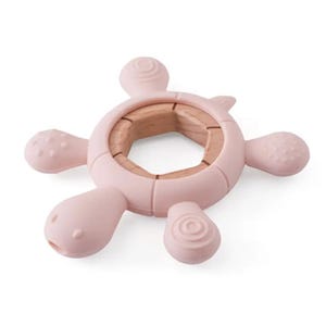 May include: A light pink baby teether shaped like a turtle. The teether has a wooden center and soft, textured silicone flippers and head. The design is intended for babies to grasp and chew on. The teether is designed to soothe sore gums.