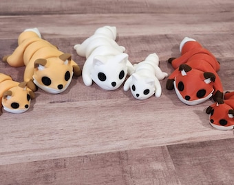 May include: Five handmade clay fox figurines in various sizes and colors. The foxes are curled up in a sleeping position with their tails wrapped around their bodies. The foxes are orange, white, and red.
