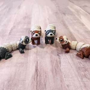 May include: Four small, segmented, plastic ferret figurines. Two are brown and white, one is gray and white, and one is black and white. The figurines are posed in a circle, facing each other.