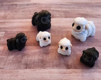 May include: A collection of handmade sheep figurines in black and white. The sheep have large, round eyes and are arranged on a wooden surface. The figurines vary in size and pose, creating a charming display.