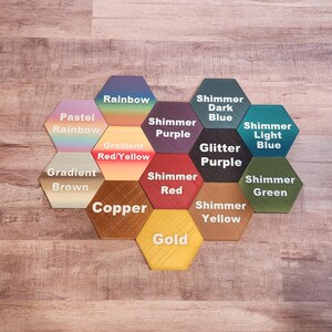 May include: A set of 12 hexagonal tiles with different colour and finish options. The tiles feature various colour gradients, shimmer effects, and glitter finishes. The tile colours include pastel rainbow, rainbow, gradient red/yellow, gradient brown, copper, gold, shimmer purple, shimmer red, shimmer yellow, shimmer green, shimmer dark blue, and shimmer light blue.