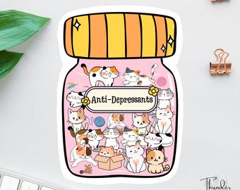 May include: A pink jar with a yellow lid filled with cartoon cats. The jar has the text "Anti-Depressants" on it.