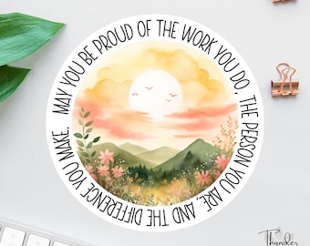 May include: A round sticker with a watercolor illustration of a sunset over mountains. The text "May you be proud of the work you do. The person you are, and the difference you make." is written around the image.