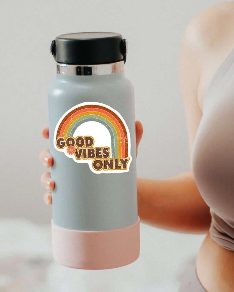 May include: A gray water bottle with a pink bottom and a rainbow sticker that says "Good Vibes Only".