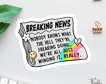 以下が含まれることがあります： 「BREAKING NEWS」の文字が上部にあるステッカー。ステッカーは新聞のデザインで、「誰も何をやっているのか知らない..私たちはみんな、本当に、即興でやっている」というテキストが入っています。スマイリーフェイス、花、虹色のハートも含まれています。