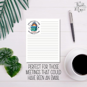 May include: A white lined notepad featuring a cartoon trash can graphic and the text "THIS LITTLE LIGHT OF MINE I'M GONNA LET IT SHINE." The notepad also has the text "PERFECT FOR THOSE MEETINGS THAT COULD HAVE BEEN AN EMAIL."