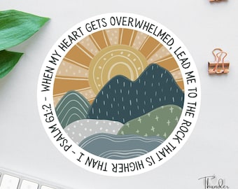 Könnte beinhalten: Ein runder Aufkleber mit einem Berg- und Sonnendesign in Blau-, Grün- und Beigetönen. Der Text "When my heart gets overwhelmed, lead me to the rock that is higher than I - Psalm 61:2" ist am Rand aufgedruckt.