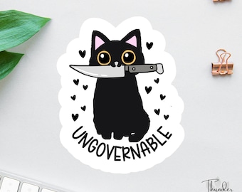 Pegatina o imán ingobernable, gato negro sarcástico con cuchillo