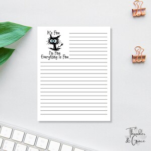 May include: White lined notepad with the text "It's Fine, I'm Fine, Everything Is Fine" and a cartoon cat illustration. The notepad has a black and white design and is suitable for taking notes or journaling.