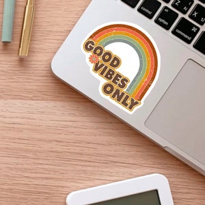 May include: A sticker with a rainbow design and the text "GOOD VIBES ONLY" in brown letters with a small flower graphic.