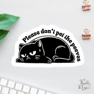 Może przedstawiać: Czarna naklejka z kotem z napisem "Please don't pet the peeves". Kreskówkowy kot leży z ponurą miną. Naklejka ma białą obwódkę i znajduje się na białej powierzchni.