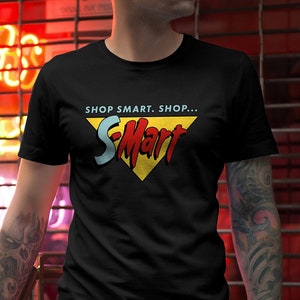 Peut inclure: Un t-shirt noir avec un graphique jaune, rouge et bleu du logo S-Mart. Le texte sur le graphique indique "Shop Smart, Shop... S-Mart".