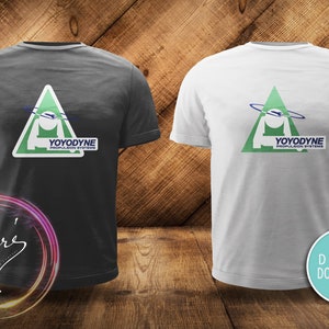 May include: Two t-shirts with a green triangle logo featuring a white spaceship and the text "YOYODYNE PROPULSION SYSTEMS". One t-shirt is dark grey and the other is white.
