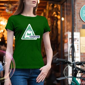 May include: A green t-shirt with a white triangle graphic featuring a stylized spaceship and the text "YOYODYNE PROPULSION SYSTEMS".