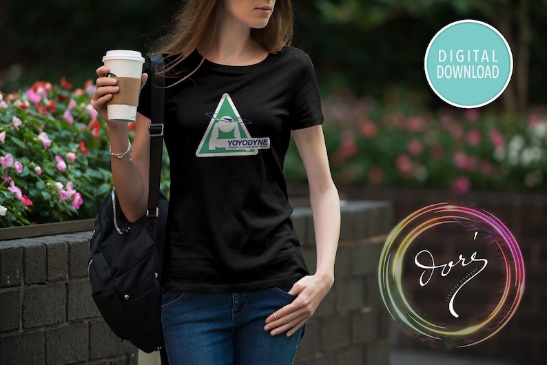 May include: A black t-shirt with a green triangle graphic featuring a white figure with a blue ring around it. The text "YOYODYNE" is printed on the graphic. The t-shirt is being worn by a person.