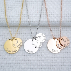 May include: Three gold, silver, and rose gold necklaces with personalized discs. The gold necklace has a disc that says "Grandma" with a smaller disc that says "J 09.12.2021". The silver necklace has a disc that says "Mom" with a smaller disc that says "T 05.11.2019". The rose gold necklace has a disc that says "Nana" with a smaller disc that says "C 08.11.2018".