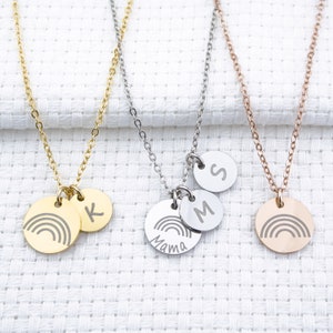 May include: Three gold, silver, and rose gold necklaces with rainbow charms and initial charms. The gold necklace has a rainbow charm and a "K" charm. The silver necklace has a rainbow charm, a "Mama" charm, and an "M" charm. The rose gold necklace has a rainbow charm and an "S" charm.