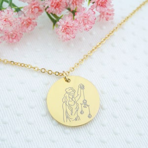 May include: Gold necklace with a round pendant featuring a line drawing of the astrological symbol for Libra, a woman holding a scale.