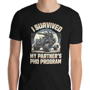 May include: Black t-shirt featuring the text "I SURVIVED MY PARTNER'S PHD PROGRAM" above a detailed illustration of a military vehicle. The graphic is in shades of grey and white, with a sun-like background.