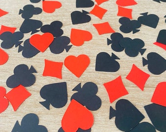 May include: A scattering of red and black card suit confetti. The confetti is in the shape of hearts, diamonds, clubs, and spades.