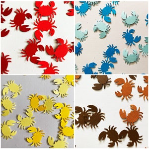May include: Assortment of paper crab cutouts in red, blue, yellow, and brown. The crabs are scattered on a white background.