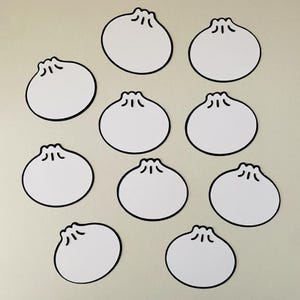 Pode incluir: Dez autocolantes brancos em forma de dumpling com contornos pretos estão dispostos sobre um fundo bege claro. Cada autocolante tem um design superior detalhado, que se assemelha a um dumpling. Os autocolantes estão espaçados uniformemente.