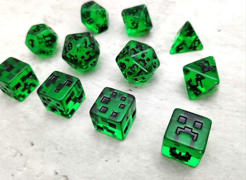 以下が含まれることがあります： ビデオゲームMinecraftのクリーパーの顔が黒く描かれた緑色のサイコロ10個のセット。サイコロは半透明で、側面にさまざまな数字が書かれています。
