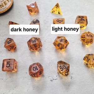 May include: A set of 10 dice in two shades of amber, labeled with black numbers. The dice are labeled "dark honey" and "light honey".
