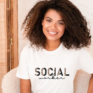 Könnte beinhalten: Ein weißes T-Shirt mit dem Aufdruck "SOCIAL worker". Die Buchstaben sind schwarz umrandet und mit einem Leopardenmuster gefüllt.