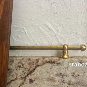 May include: A horizontal brass rod with a spherical end cap and a circular mounting bracket attached to a stone surface. The word standard is printed in white text on the lower right side of the image near the stone edge.