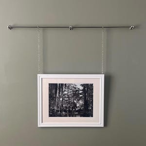 Könnte beinhalten: Eine weiße Keramik-Tasse mit schwarzem Henkel und dem Text "But First, Coffee" in schwarzer, handschriftlicher Schrift. Die Tasse steht auf einer weißen Oberfläche.