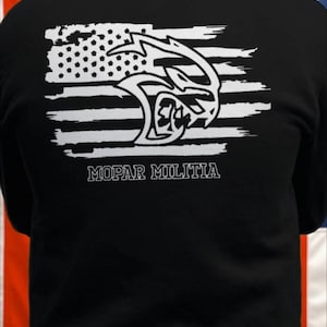 May include: Black hooded sweatshirt with a white distressed American flag design featuring a white Mopar logo and the text "Mopar Militia".