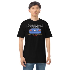 May include: A black t-shirt with a blue car illustration and the text "CARTAKUS", "MADE IN JAPAN", "TOUGE FOR LIFE", and "日本." in white and red.