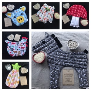 May include: A collection of quilted hot and cold packs in various animal shapes, including a cow, a chicken, a horse, and a mushroom. Each pack is accompanied by a heart-shaped bowl of rice and a small card.