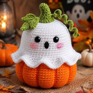 May include: A crocheted pumpkin topped with a white ghost figure. The ghost has black bead eyes, a small black oval mouth, and pink stitched cheeks. A green crocheted stem with a leaf and a curly vine sits atop the white ghost head.
