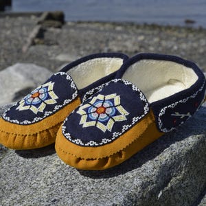 May include: A pair of blue and yellow moccasins with intricate beadwork designs. The moccasins have a soft, fuzzy lining and are perfect for keeping your feet warm in the winter.