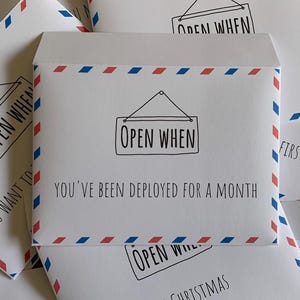 May include: A collection of white paper envelopes featuring a red and blue airmail border pattern. Each envelope displays a black line drawing of a hanging sign with the text OPEN WHEN followed by specific phrases like YOU'VE BEEN DEPLOYED FOR A MONTH.