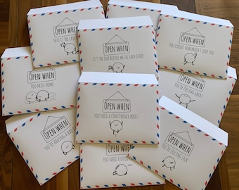 May include: A collection of white envelopes with red and blue airmail-style borders. Each envelope features a black line drawing of a character and the text "Open When" followed by specific prompts like "You need a confidence boost" or "You miss home."