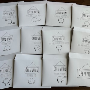 May include: A collection of white envelopes with black text and illustrations. Each envelope reads "Open When" followed by a specific occasion, such as "You're feeling stressed" or "You can't sleep". The illustrations depict simple, cartoon-like figures.