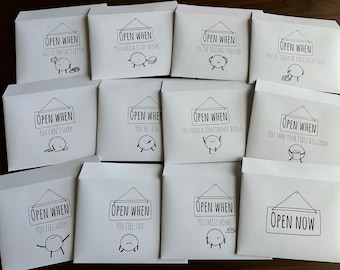 May include: A collection of white envelopes with black text and illustrations. Each envelope reads "Open When" followed by a specific occasion, such as "You're feeling stressed" or "You can't sleep". The illustrations depict simple, cartoon-like figures.