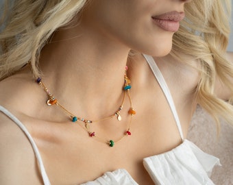 May include: A gold chain necklace with colourful beads and small charms. The necklace is layered with a second chain with smaller beads and charms.