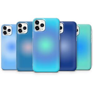 Puede incluir: Cinco fundas para teléfono de diferentes colores con un diseño degradado. Las fundas son todas transparentes y muestran las lentes de la cámara del teléfono. Los colores son azul claro, azul, turquesa, azul oscuro y verde.